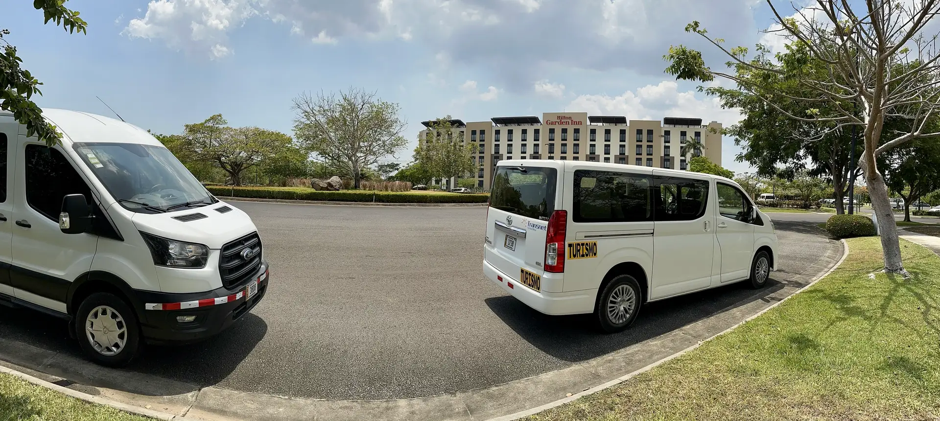 Two Transnet vans parked in front of a hotel